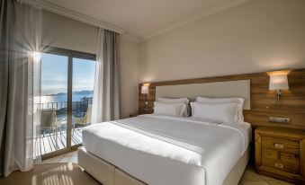 a large bed with white linens is in a hotel room with a view of the ocean at Eden Roc Hotel & Spa by Brava Hoteles