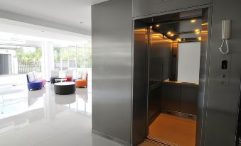 an elevator in a modern building , with a glass door revealing the interior and various furniture inside at White Inn Nongkhai Hotel