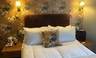 a hotel room with a king - sized bed , two lamps , and a floral wallpaper on the wall at The Ardingly Inn