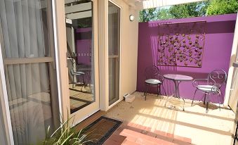 a patio area with a glass door and purple walls , featuring a table and chairs at Alexandra Place