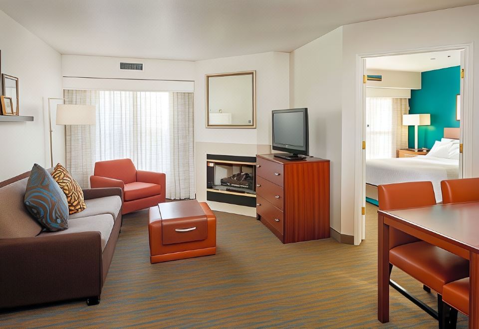 a modern hotel room with an orange leather couch , coffee table , and television , along with a bed and other amenities at Residence Inn Stockton