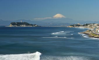 a large body of water with a mountain in the background , and boats sailing on the water at Sotetsu Fresa Inn Kamakura-Ofuna Higashiguchi