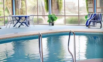 an indoor swimming pool surrounded by glass walls , with a dining table and chairs nearby at Robetown Motor Inn & Apartments
