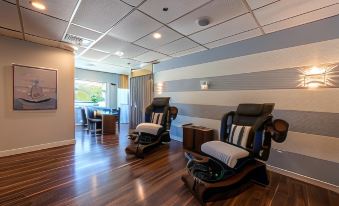 a modern office space with wooden floors , white walls , and blue striped wallpaper , featuring comfortable reclining chairs and a desk area at Georgian Bay Hotel, Trademark Collection by Wyndham