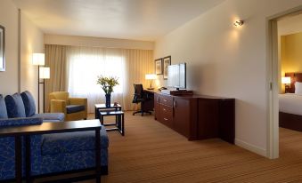 a hotel room with a couch , a tv , and a dining table , all neatly arranged at Courtyard Toluca Tollocan