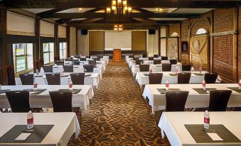 a large conference room with tables and chairs arranged in rows , along with a podium and a projector at Best Western University Inn