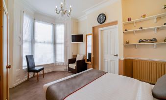a cozy hotel room with a large bed , a couch , and a tv . the room is well - appointed and inviting at Diamonds Villa Near York Hospital