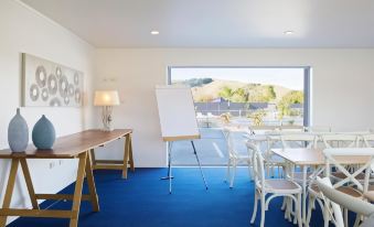 a classroom setting with white furniture , blue carpeting , and a whiteboard on the wall , along with a desk and chairs at Motel Oasis