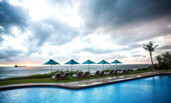 a large pool with several lounge chairs and umbrellas is surrounded by grass and the ocean at Beverly Hills