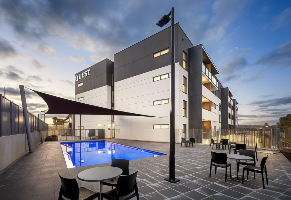a modern building with a swimming pool and outdoor seating area , under a cloudy sky at Quest Wodonga