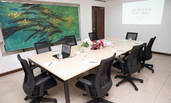 a conference room with a long table , black chairs , and a large painting on the wall at Jewels Hotel