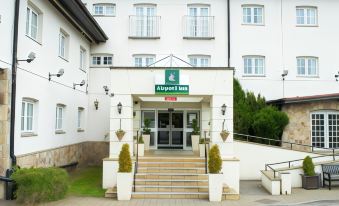 "a white building with the words "" airport inn "" prominently displayed on its front door , surrounded by green grass and trees" at Airport Inn Manchester