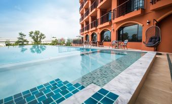 a large swimming pool with a blue tile border is situated next to an orange building at Alfahad Hotel