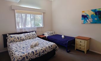 a bedroom with a blue bed and a purple table , along with a painting on the wall at Top of the Lake Holiday Units