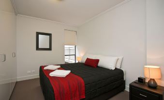 a bedroom with a black and red bedspread , white pillows , and a black dresser at The Star Apartments