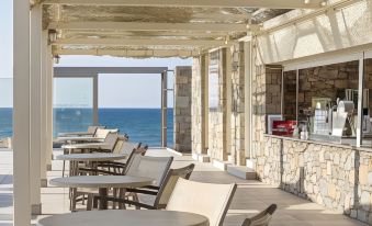 a restaurant with a view of the ocean , featuring several tables and chairs arranged for guests at Civitel Creta Beach