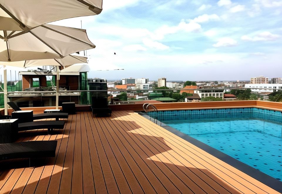 There is a rooftop swimming pool with adjacent seating area featuring chairs and tables at Aaron Vientiane Hotel
