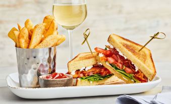 a plate with a sandwich , fries , and a glass of wine on a dining table at Courtyard New Bern