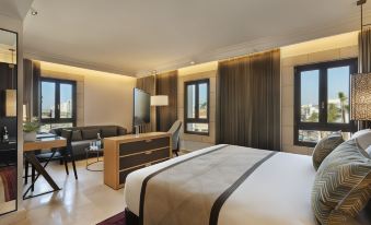 a large bed with a striped blanket is in the middle of a room with two windows at The Setai Tel Aviv, a Member of the Leading Hotels of the World