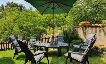 a patio set with a table and chairs under an umbrella in a lush green garden at CasAda