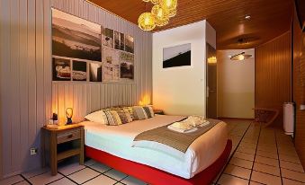 a cozy bedroom with a red bed and white walls , creating a warm and inviting atmosphere at Logis le Chalet