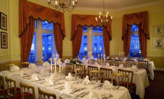 a formal dining room set up for a wedding reception , with multiple tables covered in white tablecloths and set for dinner at The Midland Hotel
