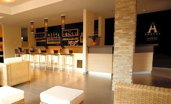 a modern restaurant with a bar area , featuring white chairs and stools , as well as a wooden bar at Ahotel Ljubljana