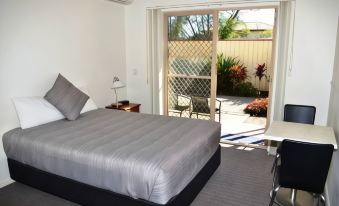 a bedroom with a bed , desk , and sliding glass doors leading to an outdoor patio at Redland Bay Motel