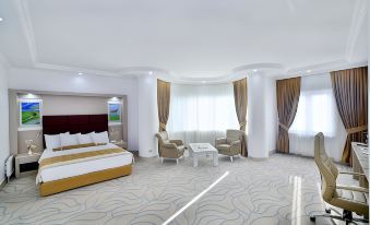 a modern hotel room with white walls , large windows , and a bed , as well as a living area with a couch and dining table at New Marathon Hotel