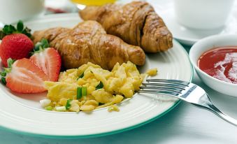 a plate of food on a dining table , consisting of scrambled eggs , croissants , and a cup of coffee at Home2 Suites by Hilton Downingtown Exton Route 30
