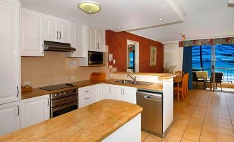 a modern kitchen with white cabinets , a wooden countertop , and an open floor plan kitchen at Coolum Caprice