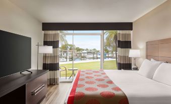 a bedroom with a large bed and sliding glass doors leading to an outdoor patio at Ramada by Wyndham Sarasota Waterfront