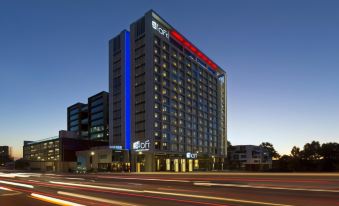 "a tall , modern building with the logo "" fox "" on it is lit up at night" at Aloft Perth