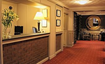 a hotel lobby with a reception desk , lamps , and framed pictures on the wall , as well as a hallway with a bed at Birch Hotel