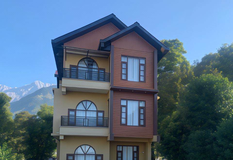 a two - story building with a brown and yellow exterior is surrounded by trees and mountains at The Sojourn