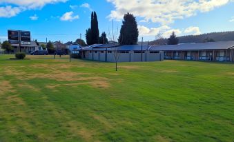 a grassy field with two buildings in the background , one on the left and the other on the right at Zig ZAG Motel & Apartments