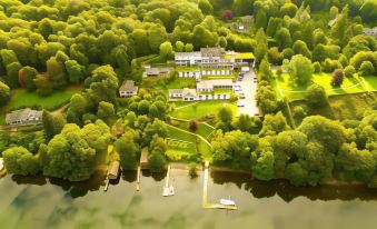 aerial view of a large house surrounded by trees , with a body of water in the background at Beech Hill Hotel & Spa