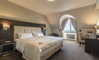 a large bed with white linens is situated in a room with a chair and window at Hotel Victory