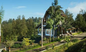 a beautiful house with a large porch and several trees , situated on a hillside near a body of water at Plataran Bromo