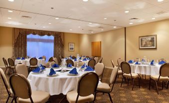 a well - decorated banquet hall with round tables covered in white tablecloths and blue napkins , ready for a meal at DoubleTree by Hilton Hartford - Bradley Airport