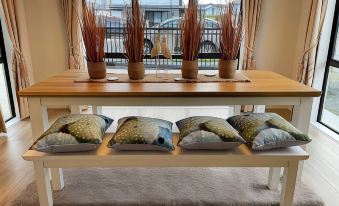 a dining room with a table and chairs , along with a bench with several decorative pillows at Flat Bush Holiday Accomodation