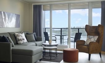 a living room with a couch , chairs , and ottoman is shown with a view of the ocean through large windows at Son Spa, an Ascend Member