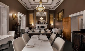 a large , elegant dining room with multiple tables and chairs set for a formal dinner at Quamby Estate