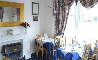 a dining room with blue tablecloths and chairs , a fireplace , and a vase of flowers at Diamonds Villa Near York Hospital