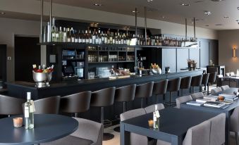 a modern restaurant with a bar area , where several people are seated and enjoying their meals at Fletcher Hotel - Restaurant Nautisch Kwartier