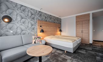 a modern hotel room with a gray bed , wooden headboard , and a small table next to the bed at Hotel Adler - Paulas Alb