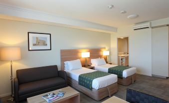 a modern hotel room with two beds , a couch , and a coffee table , all arranged in the space at Bunbury Hotel Koombana Bay