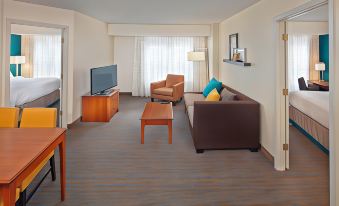 a living room with a brown couch , wooden coffee table , and a flat - screen tv mounted on the wall at Residence Inn Hartford Avon