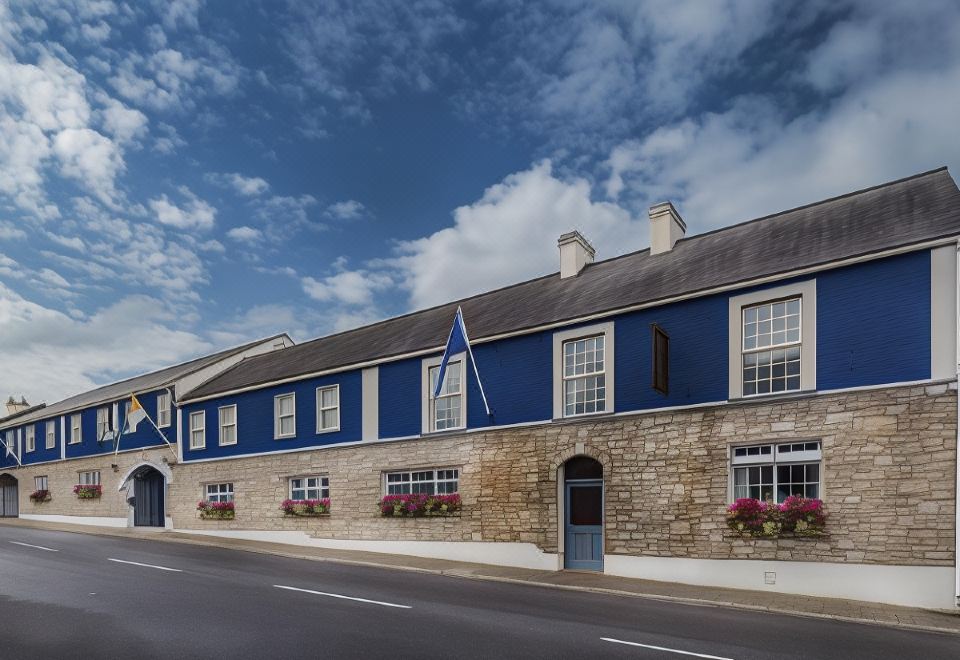 a blue and white building with a flag on the side , situated in front of a stone wall at Breffni Arms Hotel