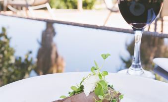 a plate of food is on a table with a glass of wine and chairs in the background at Parklands Resort Mudgee